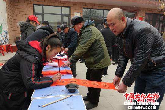 图为王道合的小侄女给村民们写春联。　张帆 摄
